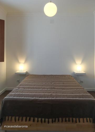 a bed in a room with two lights on the wall at casas da Baronia casa Catarina in Vila Nova da Baronia