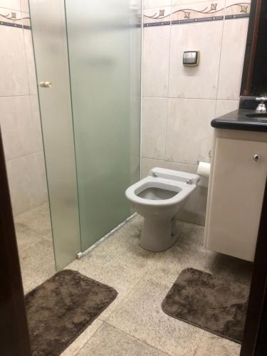 a bathroom with a toilet and a glass shower stall at Quarto com varanda tipo Airbn b Vista Panorâmica Livre da Cidade in Americana