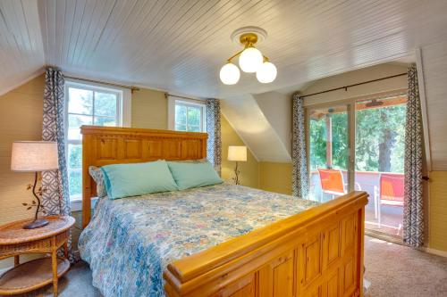 a bedroom with a bed with a wooden headboard and windows at Historic Mapleton Cottage with River Views and Hot Tub in Mapleton