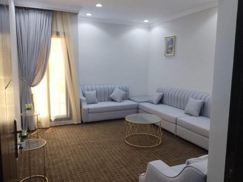 a living room with a couch and two tables at شقق الكوثر الفندقية in Makkah