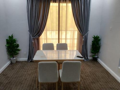 Habitación con mesa, sillas y ventana en شقق الكوثر الفندقية en Makkah