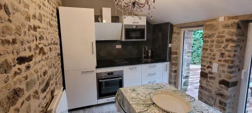 - une cuisine avec des placards blancs et un mur en pierre dans l'établissement Maison à la campagne, 