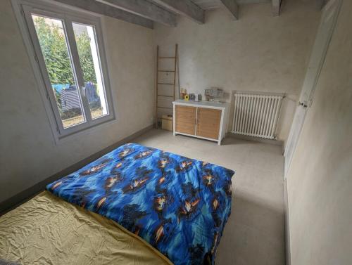 een slaapkamer met een bed met een blauw dekbed en een raam bij Le Nid de Mazerolles in Sucé