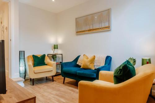 a living room with two chairs and a blue couch at Mayfield Two - Central Harrogate Apartment in Harrogate