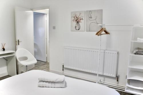 Cette chambre blanche dispose d'un lit et d'une chaise blancs. dans l'établissement Hackney Haven!, à Londres