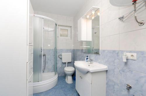 a white bathroom with a toilet and a sink at Apartments Mirjana in Vodice
