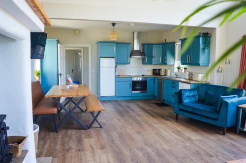 cocina con armarios azules, mesa y sillas en Cuilcagh Croft - Fermanagh Lakelands, en Enniskillen