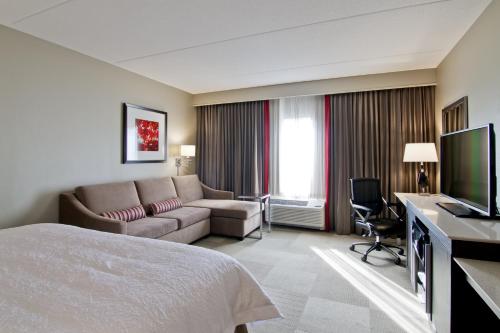 a hotel room with a bed and a couch at Hampton Inn & Suites by Hilton Toronto Markham in Markham