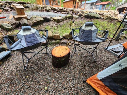 two chairs and a tree stump with a tent at Deluxe tent in Butler