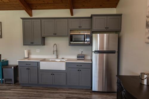 uma cozinha com armários cinzentos e um frigorífico de aço inoxidável em Stony Fork Inn em Wellsboro