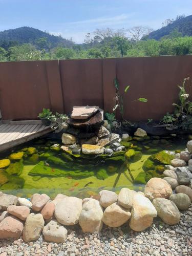 Pousada Vô Lica com piscina في بنها: بركة أسماك كوي مع جسر وبعض الصخور