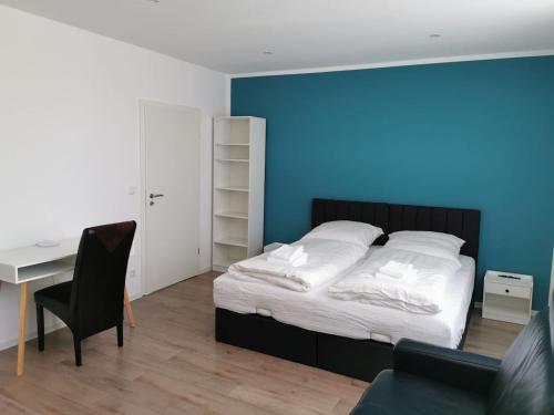 1 dormitorio con 1 cama con escritorio y pared azul en Ferienwohnung 303 am Kasinopark, en Georgsmarienhütte