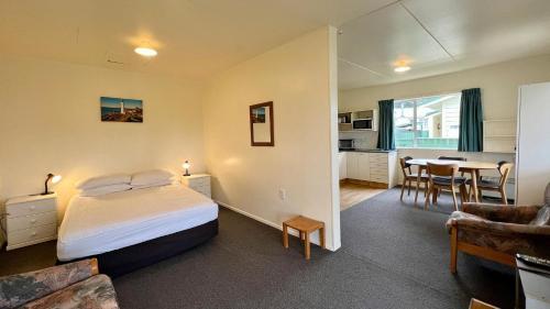 a bedroom with a bed and a dining room at Castlepoint Holiday Park & Motels in Castlepoint