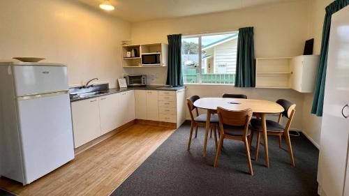 a kitchen with a table and chairs and a refrigerator at Castlepoint Holiday Park & Motels in Castlepoint