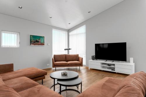 a living room with a couch and a flat screen tv at Luxury Villa with River View in Laugaras