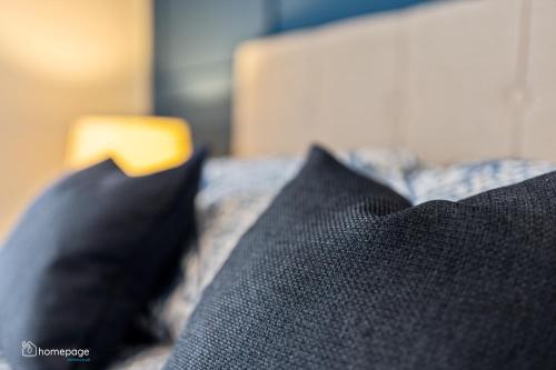 a pile of black pillows on a bed at Luxury Apartment - Roe Getaway Limavady in Limavady