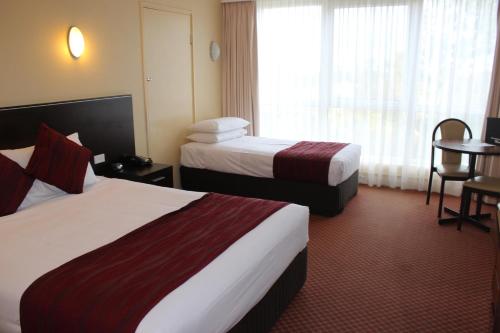 a hotel room with two beds and a table at Alpine Motor Inn in Katoomba