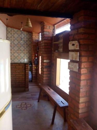 um quarto com um banco de madeira numa parede de tijolos em Espaço Alternativo - a sua casa em Carmo do Rio Claro em Carmo do Rio Claro