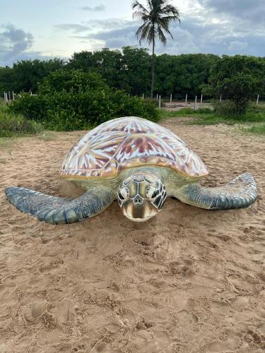 a statue of a turtle on the sand at Pousada Dona Felicidade Carneiros in Tamandaré