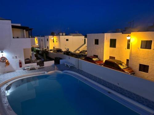 a swimming pool on the roof of a building at night at Moderno apartamento cerca al mar in Tías