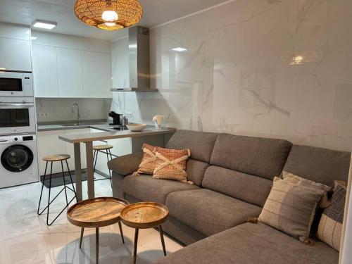 a living room with a couch and tables and a kitchen at Moderno apartamento cerca al mar in Tías