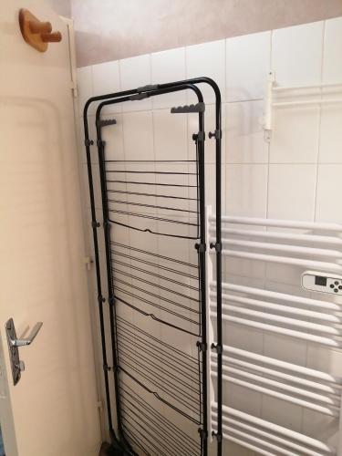 La salle de bains est pourvue d'une porte de douche et de carrelage blanc. dans l'établissement Appartement meublé 1 étoile - Tourisme tout confort - Cures et Courts séjours - Les Mascareignes, à Châtel-Guyon