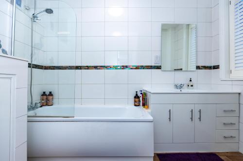 a white bathroom with a tub and a sink at Raven Haven Glastonbury in Glastonbury