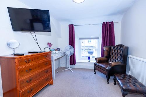 a living room with a dresser with a television and a chair at Raven Haven Glastonbury in Glastonbury