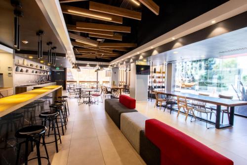 un restaurant avec un bar, des tables et des chaises dans l'établissement ibis Tijuana, à Tijuana