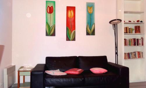 マントンにあるLa Maison au Soleilの黒いソファ(壁に4点の絵画が飾られたリビングルーム)