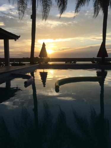 a pool with the sunset in the background at Pousada Sobre as Águas in São João da Barra