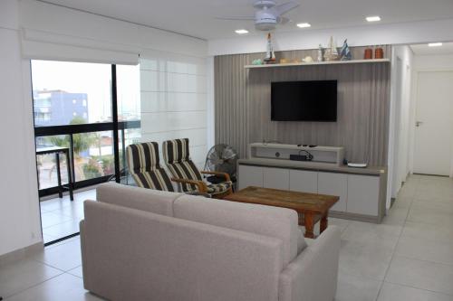 a living room with a couch and a tv at Uma quadra da praia - Vista para o Mar - Guaratuba - AC e Wi-Fi in Guaratuba