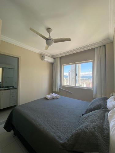 - une chambre avec un grand lit et une fenêtre dans l'établissement Apartamento com sacada e churrasqueira, à Balneário Camboriú