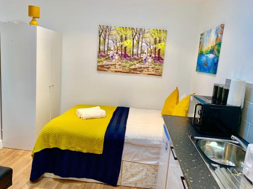 een kleine slaapkamer met een bed en een wastafel bij London Studio Apartments Close to Station NP4 in Londen