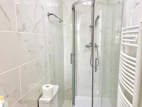 a white bathroom with a shower and a toilet at London Studio Apartments Close to Station NP4 in London