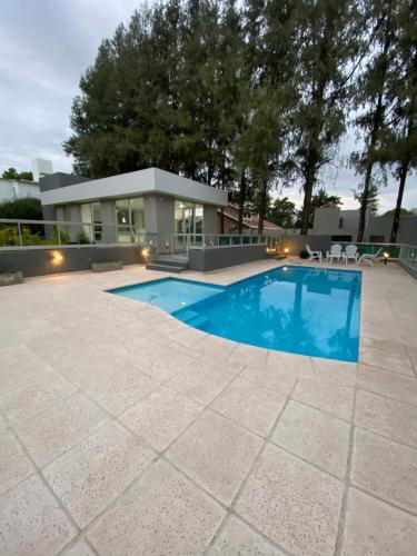 a swimming pool in front of a house at Departamento impecable ,complejo cerrado, asador y pileta in Villa Allende