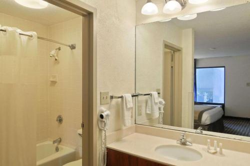 a bathroom with a sink and a large mirror at Baymont by Wyndham Macon I-75 in Macon