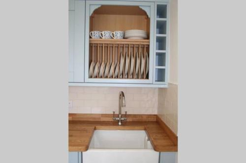 a kitchen with a sink and a shelf with dishes at Travershes Holiday Cottage in Exmouth