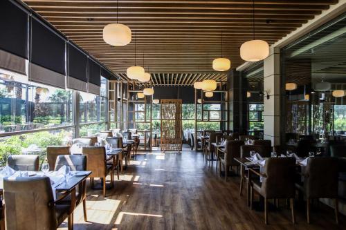 a dining room with tables and chairs and windows at Best Western Premier Karsiyaka Convention & Spa Hotel in Izmir