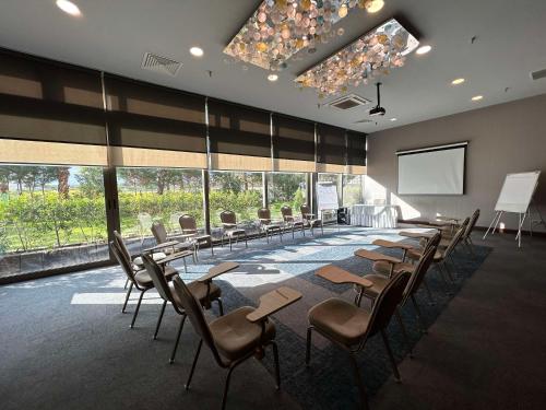 a conference room with tables and chairs and a screen at Best Western Premier Karsiyaka Convention & Spa Hotel in Izmir