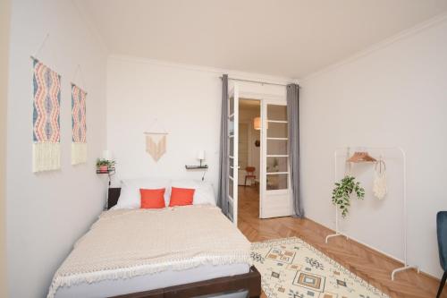 um quarto branco com uma cama com almofadas laranja em Castle Nest Apartment em Budapeste