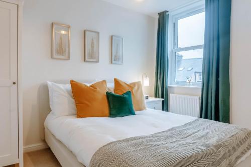 a bedroom with a bed with orange and green pillows at Mayfield Three - Central Harrogate Apartment in Harrogate