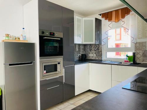 una cocina con electrodomésticos de acero inoxidable y armarios blancos en Ferienhaus JoNa - 4 Zimmer & 2 Bäder, en Oberwesel