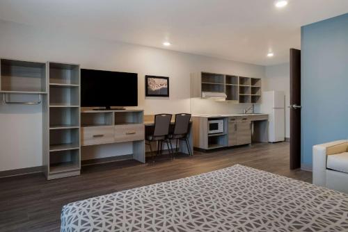 a room with a bed and a desk with a television at WoodSpring Suites Detroit Sterling Heights in Sterling Heights