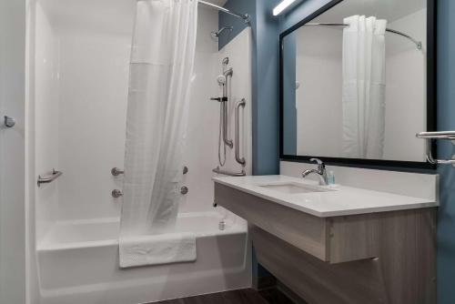 a bathroom with a shower and a sink and a tub at WoodSpring Suites Detroit Sterling Heights in Sterling Heights