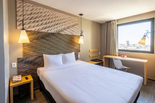 um quarto de hotel com uma cama grande e uma janela em ibis Tijuana em Tijuana
