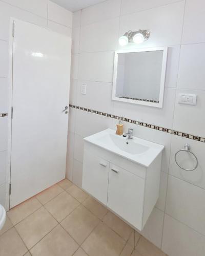 Baño blanco con lavabo y espejo en Casa Nuup en Río Tercero