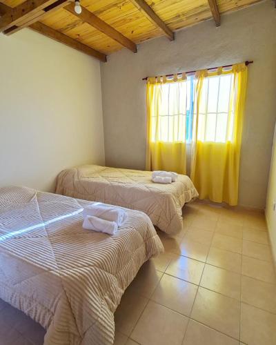 1 dormitorio con 2 camas y una ventana con cortinas amarillas en Casa Nuup en Río Tercero