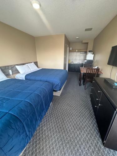 a hotel room with two beds and a desk at Voyageur Motel in Rocky Mountain House