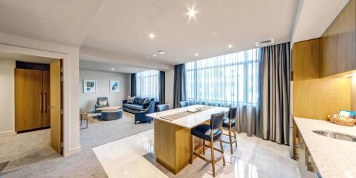 a kitchen and living room with a table and chairs at Distinction Dunedin Hotel in Dunedin